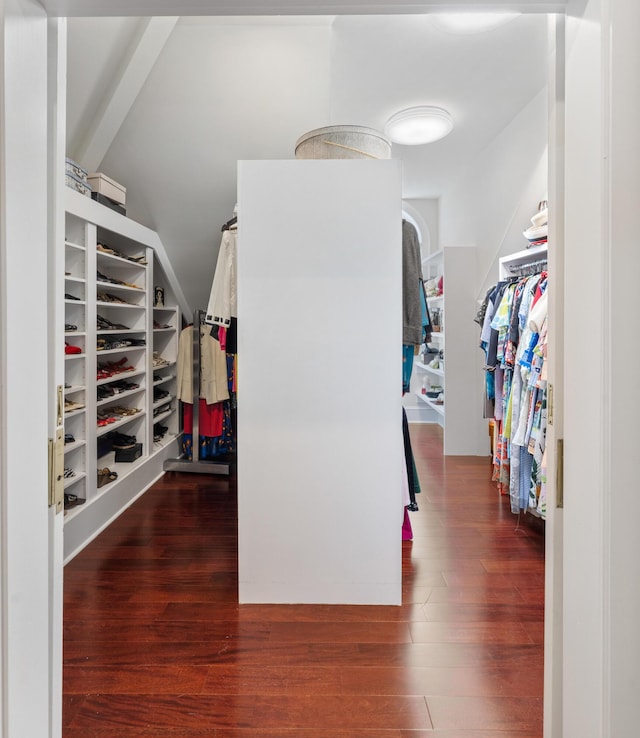 spacious closet with lofted ceiling with beams and dark wood-type flooring