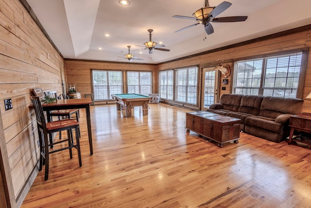 living room with ceiling fan, light wood-type flooring, wood walls, and billiards