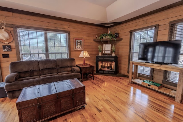 living room featuring light hardwood / wood-style flooring, wooden walls, and plenty of natural light