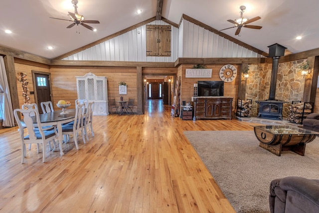 living room with ceiling fan, a wood stove, and light wood-type flooring