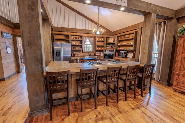 interior space featuring decorative light fixtures, built in features, stainless steel appliances, a notable chandelier, and light hardwood / wood-style flooring