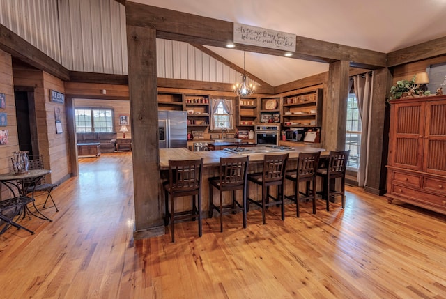 kitchen featuring a notable chandelier, a kitchen breakfast bar, stainless steel appliances, and light wood-type flooring