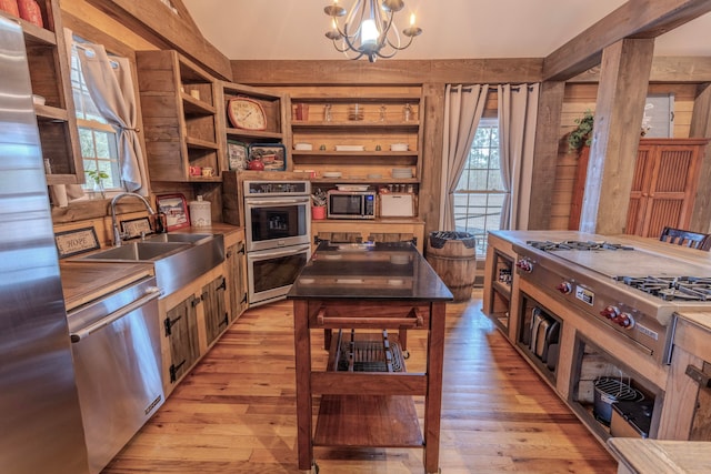 kitchen with an inviting chandelier, appliances with stainless steel finishes, light wood-type flooring, a center island, and sink