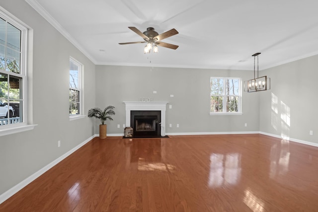 unfurnished living room featuring hardwood / wood-style flooring, ceiling fan with notable chandelier, and ornamental molding