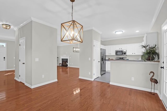 kitchen with dark wood-type flooring, an inviting chandelier, hanging light fixtures, appliances with stainless steel finishes, and white cabinets