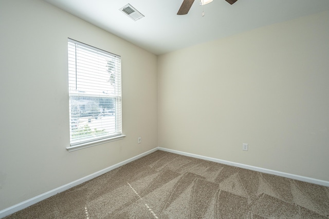 carpeted spare room featuring visible vents, ceiling fan, and baseboards