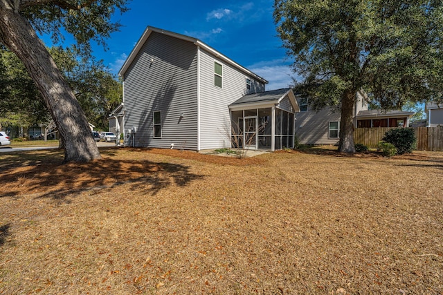 rear view of house featuring a sunroom, fence, and a yard