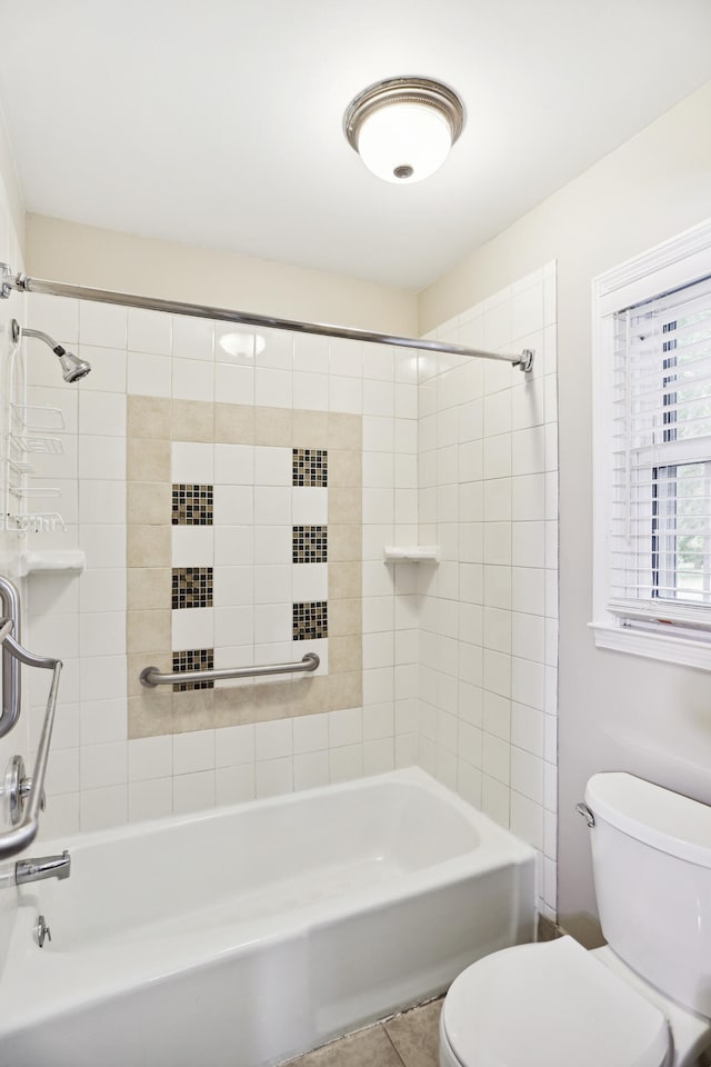 bathroom with tiled shower / bath combo, toilet, and tile patterned flooring