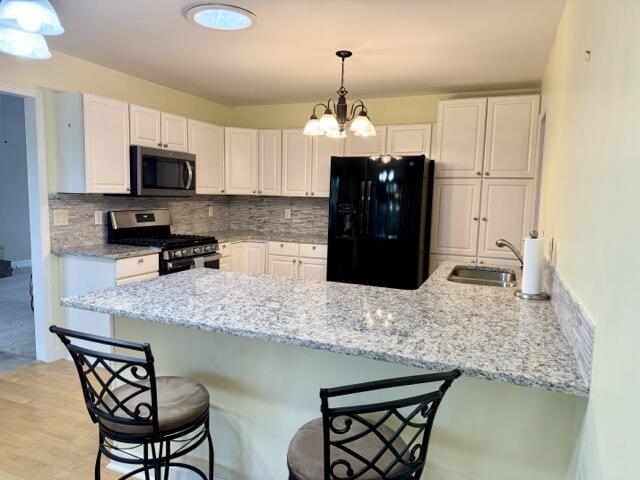 kitchen with appliances with stainless steel finishes, a kitchen bar, kitchen peninsula, and sink