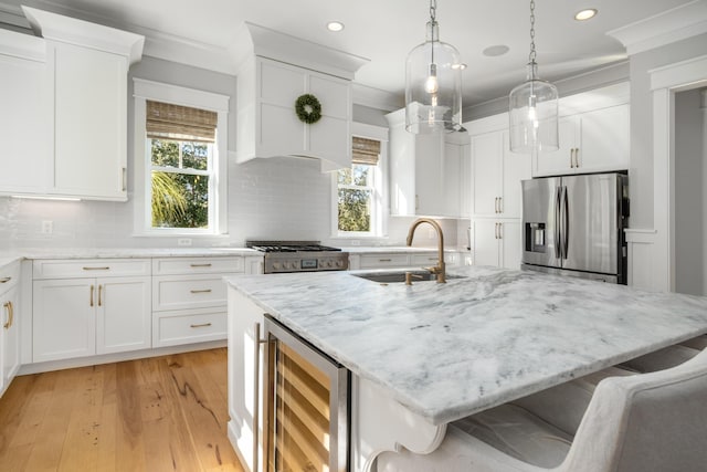 kitchen with white cabinets, a center island with sink, sink, stainless steel fridge, and beverage cooler