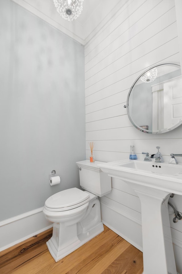 bathroom with an inviting chandelier, wood-type flooring, and toilet