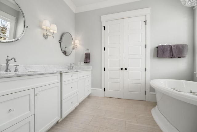 bathroom featuring a washtub, ornamental molding, and vanity