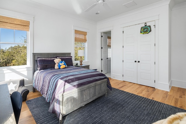 bedroom with hardwood / wood-style floors, a closet, ceiling fan, and ornamental molding