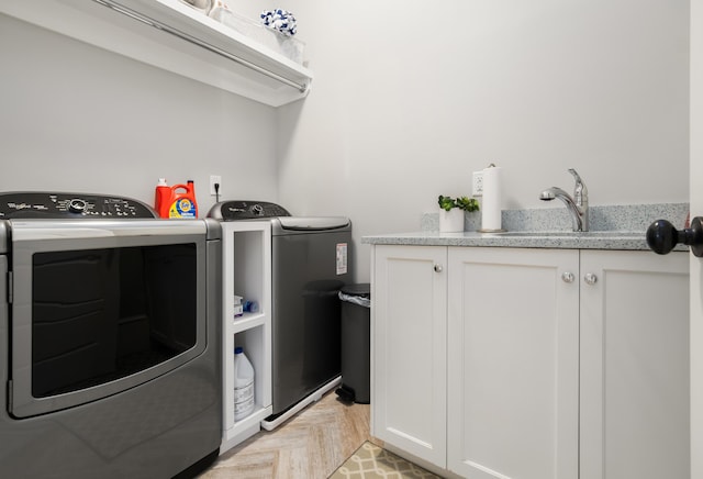 laundry room featuring washer and clothes dryer, light parquet floors, cabinets, and sink