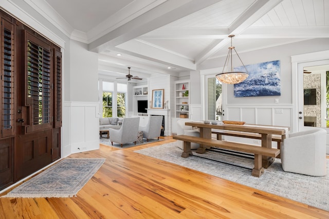 dining area featuring ornamental molding, ceiling fan with notable chandelier, beam ceiling, hardwood / wood-style flooring, and built in features