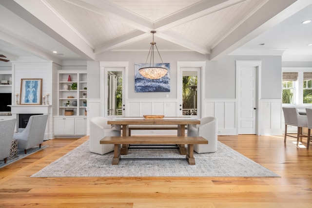 dining space featuring beam ceiling, light wood-type flooring, built in features, and ornamental molding