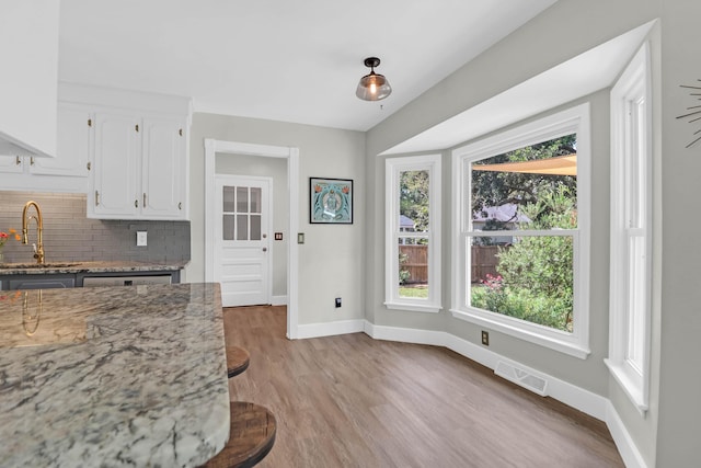 1468 N Relyea Ave, Charleston, SC 29412 - kitchen with decorative backsplash, white cabinets, light wood finished floors, and light stone counters