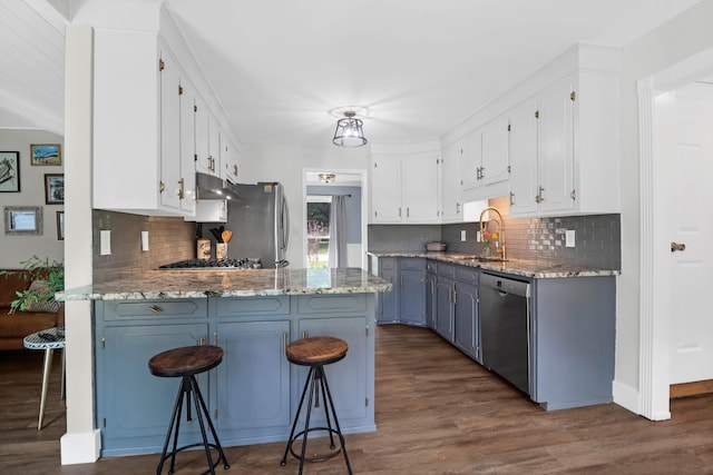 1468 N Relyea Ave, Charleston, SC 29412 - kitchen with appliances with stainless steel finishes, a peninsula, white cabinetry, under cabinet range hood, and dark wood-type flooring