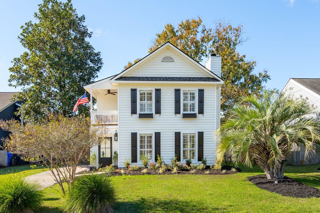 view of front of property with ceiling fan, a balcony, and a front yard