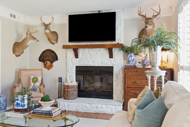 interior space featuring hardwood / wood-style flooring, a stone fireplace, and ornamental molding