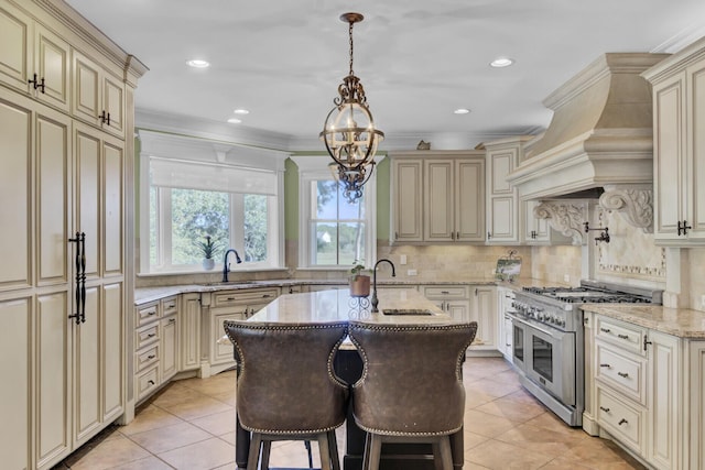 kitchen featuring double oven range, cream cabinets, light stone countertops, an island with sink, and a kitchen bar