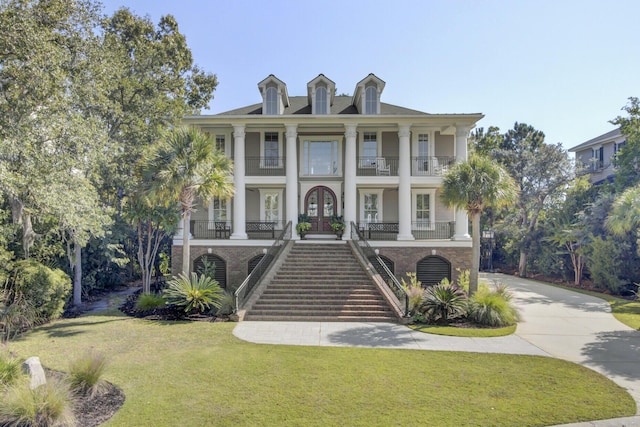 view of front facade featuring a porch, a front yard, and french doors