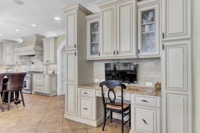 kitchen with stainless steel range, custom range hood, tasteful backsplash, and ornamental molding