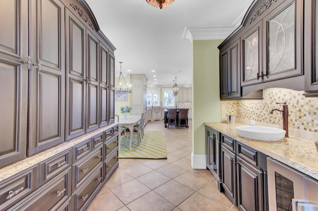 kitchen with crown molding, sink, hanging light fixtures, light tile patterned flooring, and beverage cooler