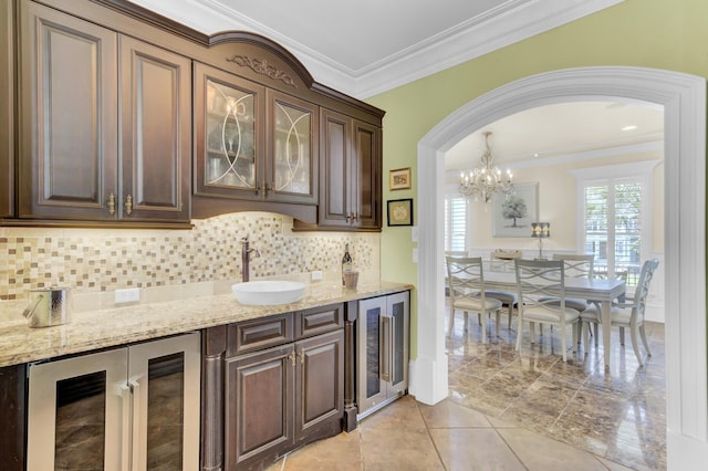 kitchen featuring dark brown cabinetry, wine cooler, ornamental molding, and backsplash