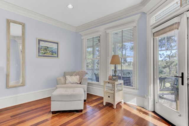 living area with a healthy amount of sunlight, wood-type flooring, and ornamental molding