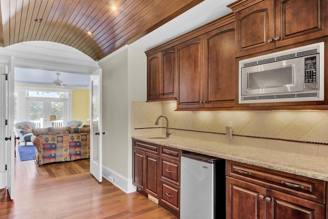 kitchen featuring stainless steel microwave, french doors, sink, fridge, and light wood-type flooring