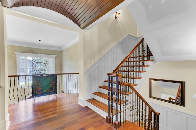 staircase with hardwood / wood-style flooring, crown molding, and a chandelier