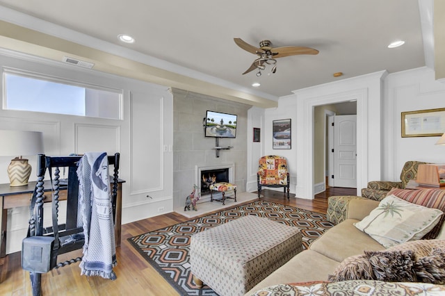 living room with a tile fireplace, ceiling fan, and hardwood / wood-style flooring