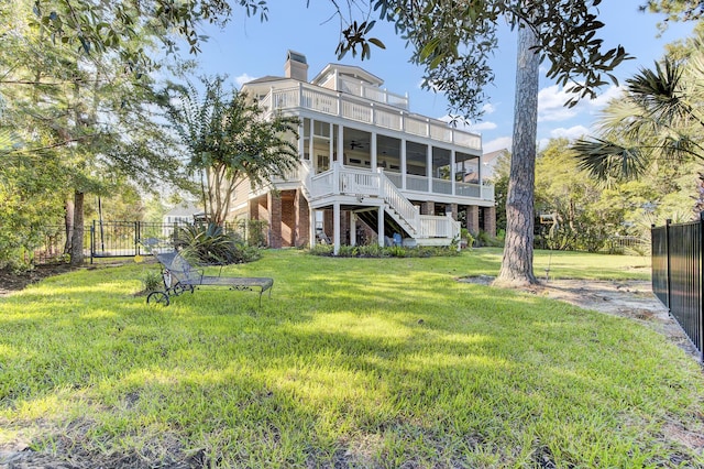 rear view of house featuring a yard, a sunroom, ceiling fan, and a balcony