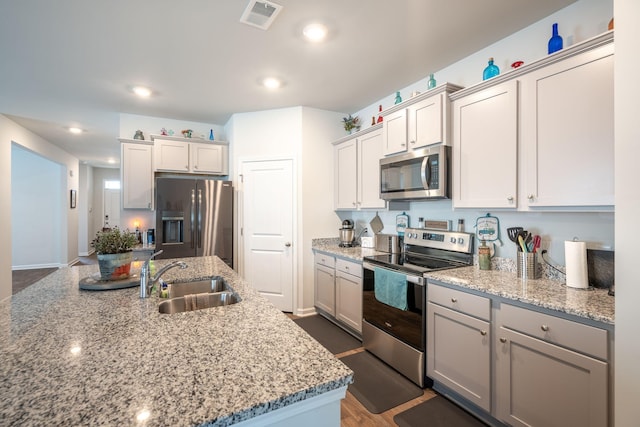 kitchen with dark hardwood / wood-style flooring, stainless steel appliances, light stone counters, and sink