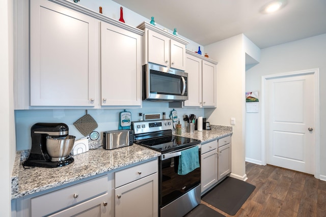 kitchen featuring light stone countertops, white cabinetry, appliances with stainless steel finishes, and dark hardwood / wood-style floors