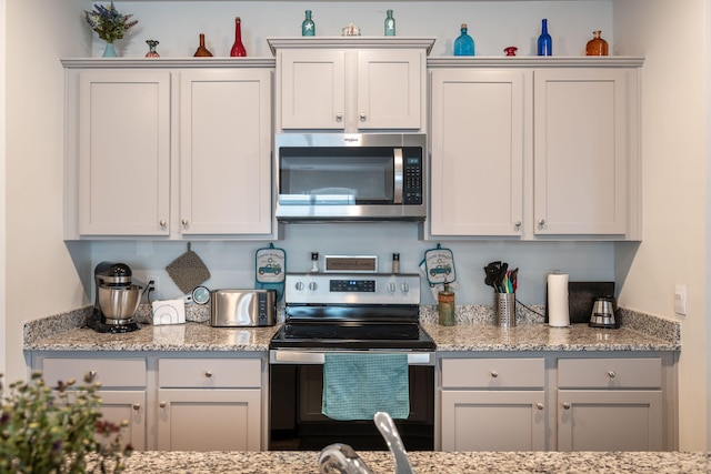 kitchen featuring light stone counters, appliances with stainless steel finishes, and white cabinetry