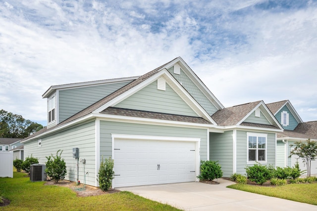 view of front of property with a front yard, central air condition unit, and a garage