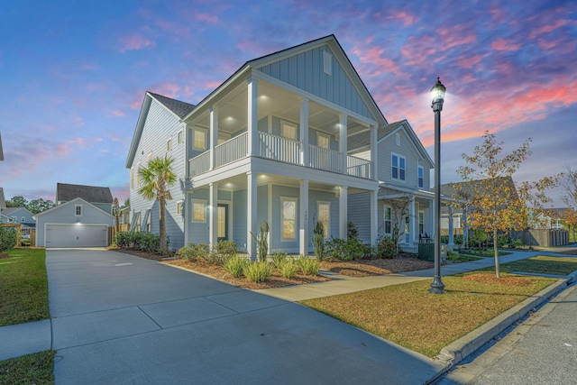 view of front of property featuring a lawn, an outdoor structure, a balcony, covered porch, and a garage