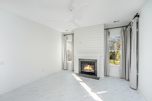 unfurnished living room with ceiling fan and a large fireplace