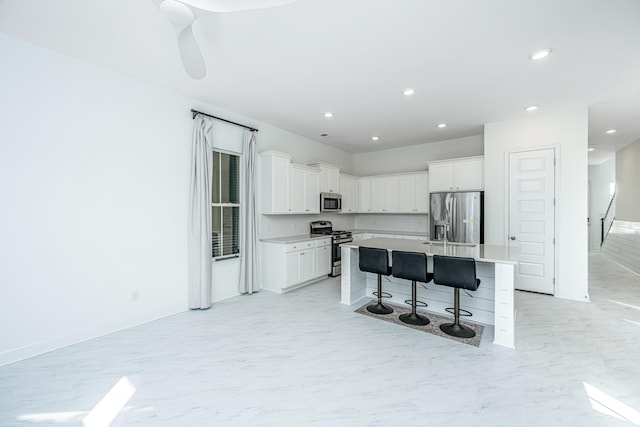 kitchen featuring white cabinets, a kitchen breakfast bar, a kitchen island with sink, and stainless steel appliances