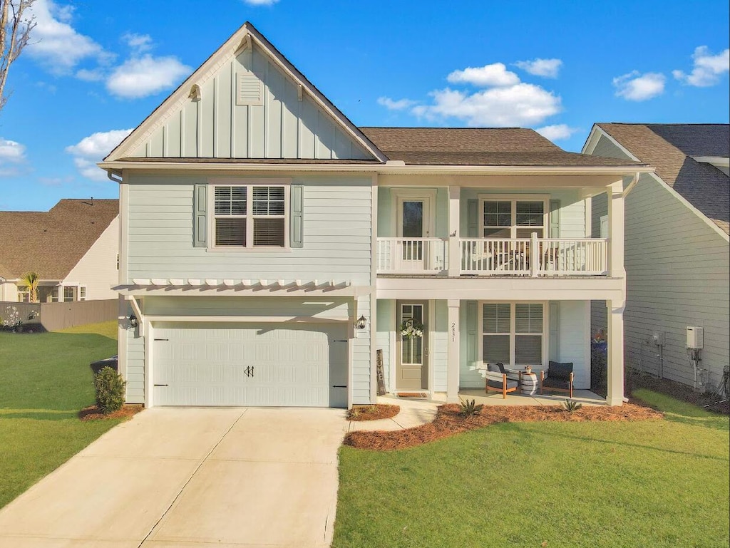 view of front of house featuring a balcony, a front yard, and a garage