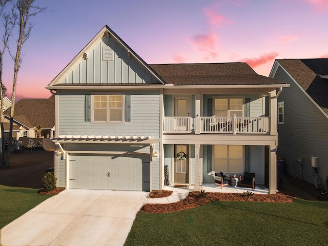 view of front of house with a balcony, a yard, covered porch, and a garage