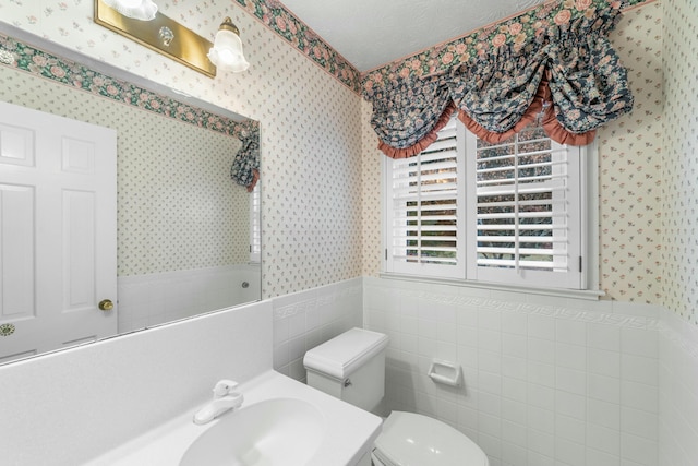 bathroom featuring vanity, toilet, and tile walls