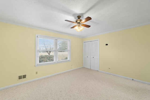 carpeted spare room featuring a textured ceiling, ceiling fan, and crown molding