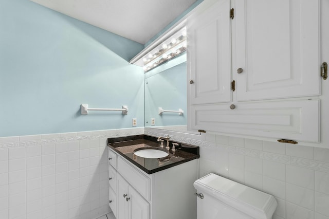 bathroom with vanity, toilet, and tile walls