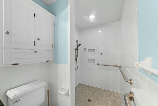 bathroom featuring tile patterned floors, toilet, a tile shower, and tile walls