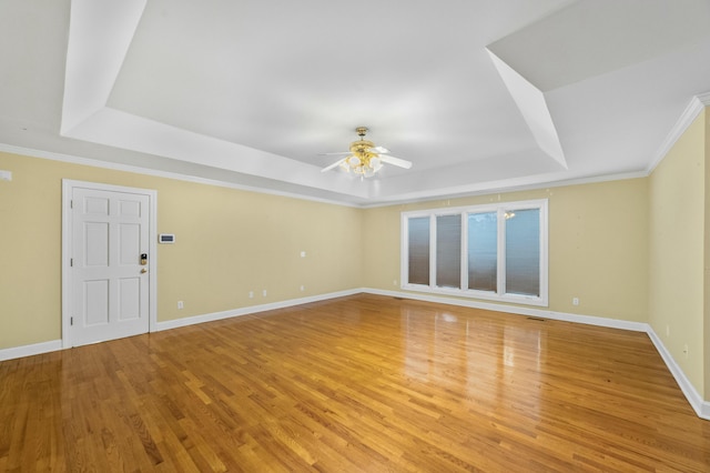 unfurnished room featuring hardwood / wood-style flooring, a raised ceiling, ceiling fan, and crown molding