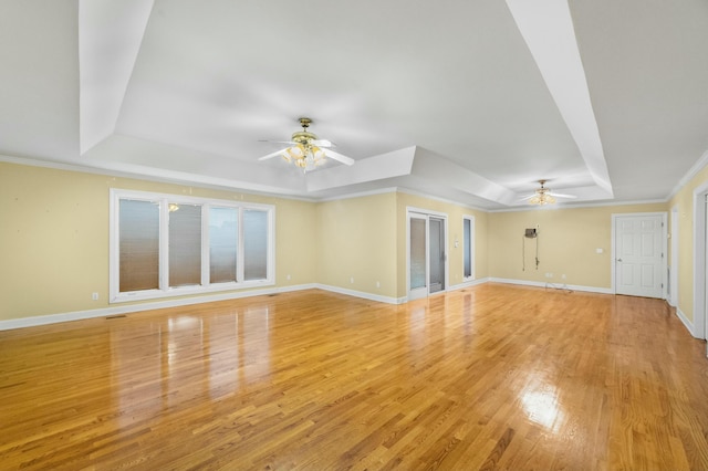 unfurnished living room with ceiling fan, light wood-type flooring, ornamental molding, and a tray ceiling