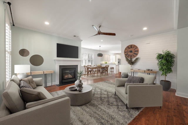 living room featuring dark hardwood / wood-style floors, ceiling fan, and crown molding